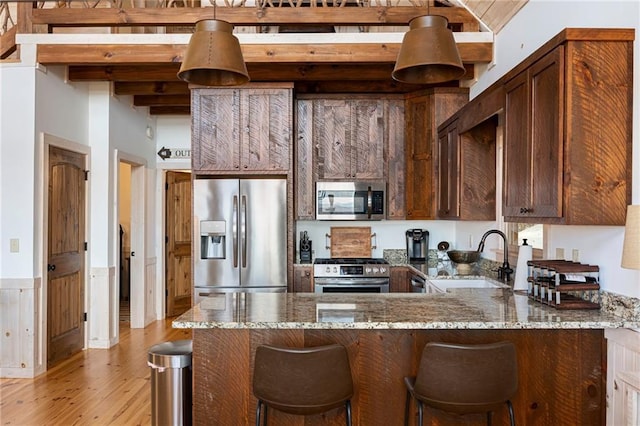 kitchen with dark stone counters, light hardwood / wood-style flooring, beamed ceiling, stainless steel appliances, and sink