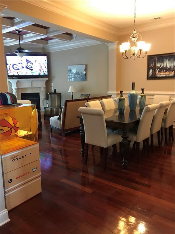 1175 Grassy Oat Ln, Lawrenceville, GA 30045 - dining space featuring a chandelier, ornamental molding, dark wood-style floors, coffered ceiling, and a fireplace