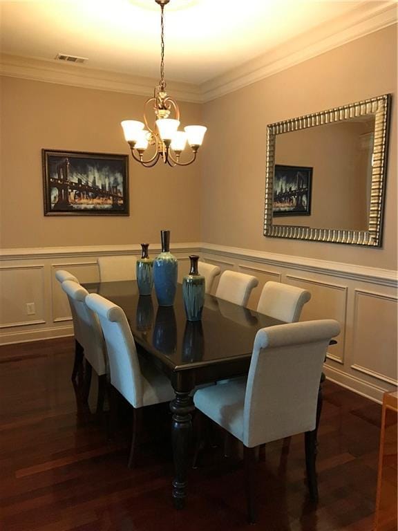 1175 Grassy Oat Ln, Lawrenceville, GA 30045 - dining space featuring crown molding, a decorative wall, a chandelier, dark wood-style floors, and wainscoting