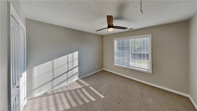 empty room featuring a ceiling fan, carpet, baseboards, and a textured ceiling