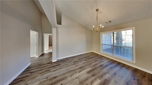 spare room featuring lofted ceiling, a textured ceiling, wood finished floors, visible vents, and baseboards