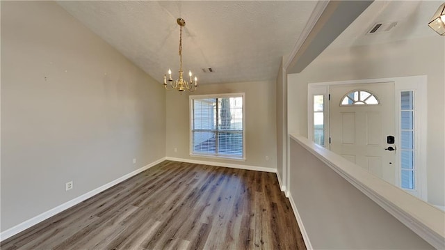 foyer entrance with visible vents, a notable chandelier, baseboards, and wood finished floors