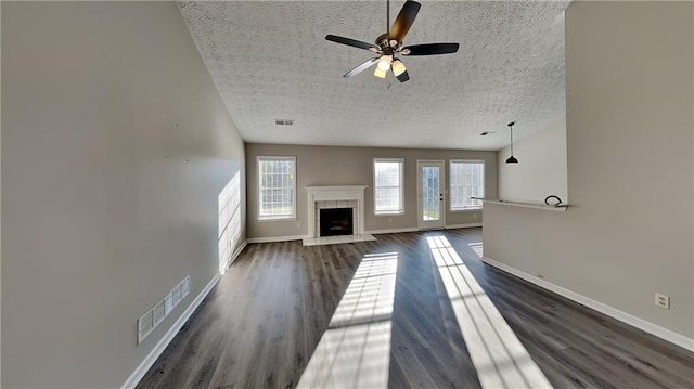 unfurnished living room with baseboards, visible vents, dark wood finished floors, and a textured ceiling