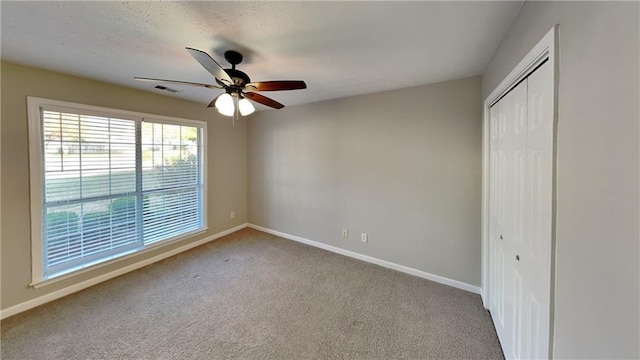 unfurnished bedroom with carpet, a closet, visible vents, a ceiling fan, and baseboards