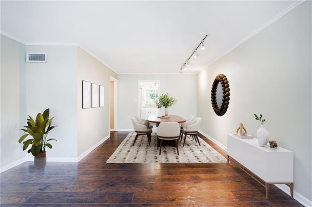 dining space featuring rail lighting, dark hardwood / wood-style floors, and crown molding