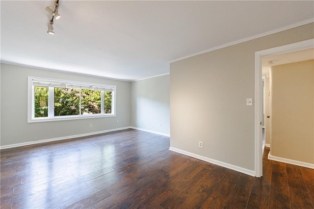 spare room featuring dark wood-type flooring, ornamental molding, and rail lighting