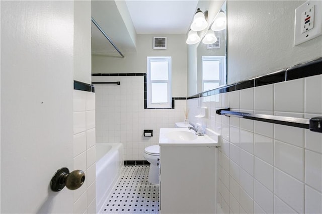 full bathroom featuring toilet, shower / tub combination, tile walls, tile patterned floors, and vanity