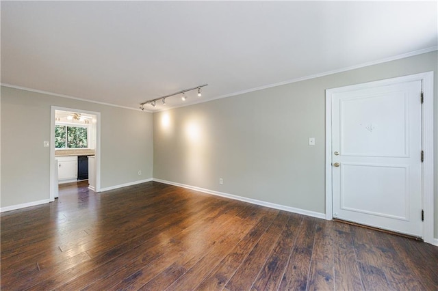 empty room with track lighting, crown molding, and dark hardwood / wood-style floors