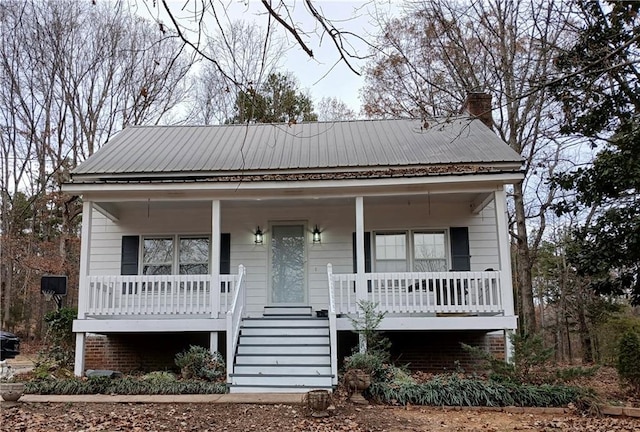 view of front of house with a porch, metal roof, and a chimney