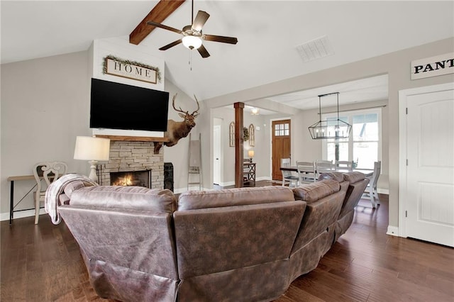 living room with ceiling fan, dark hardwood / wood-style floors, lofted ceiling with beams, and a stone fireplace