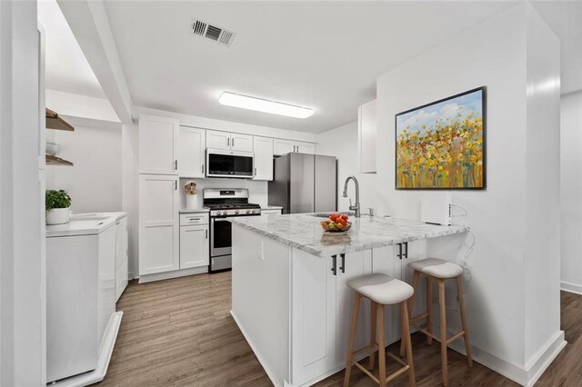 1379 Keys Lake Dr NE, Brookhaven, GA 30319 - kitchen with visible vents, washing machine and dryer, a peninsula, stainless steel appliances, and a sink