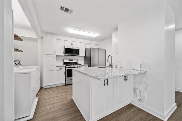 1379 Keys Lake Dr NE, Brookhaven, GA 30319 - kitchen featuring visible vents, a sink, washing machine and dryer, stainless steel appliances, and a peninsula