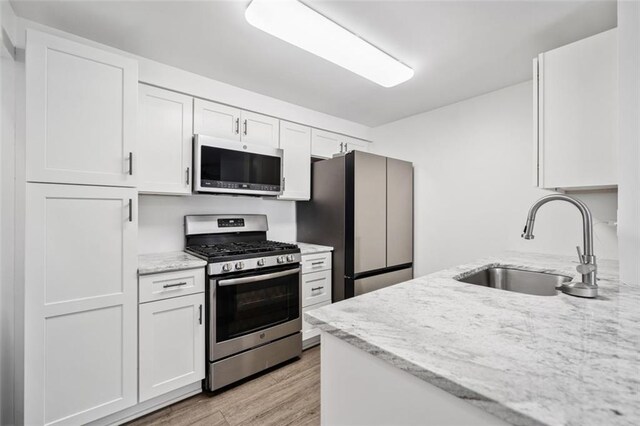 1379 Keys Lake Dr NE, Brookhaven, GA 30319 - kitchen with light wood finished floors, stainless steel range with gas cooktop, light stone countertops, white cabinets, and a sink