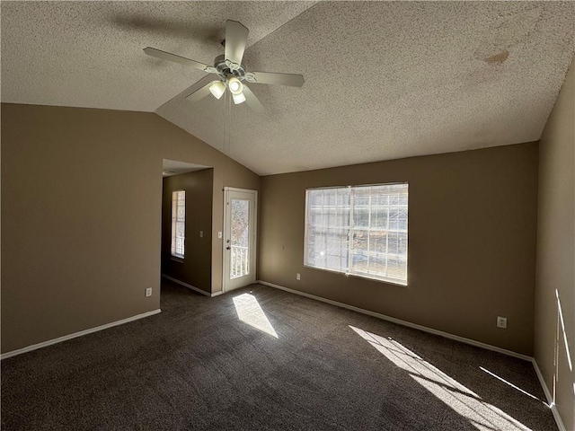 interior space featuring dark colored carpet, ceiling fan, lofted ceiling, and a textured ceiling