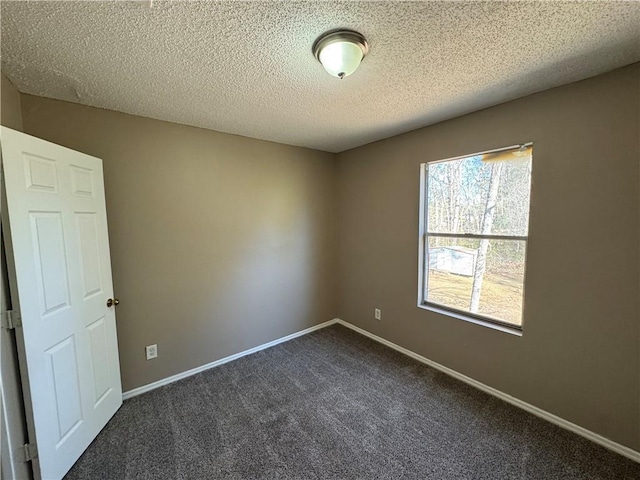 empty room with dark colored carpet and a textured ceiling