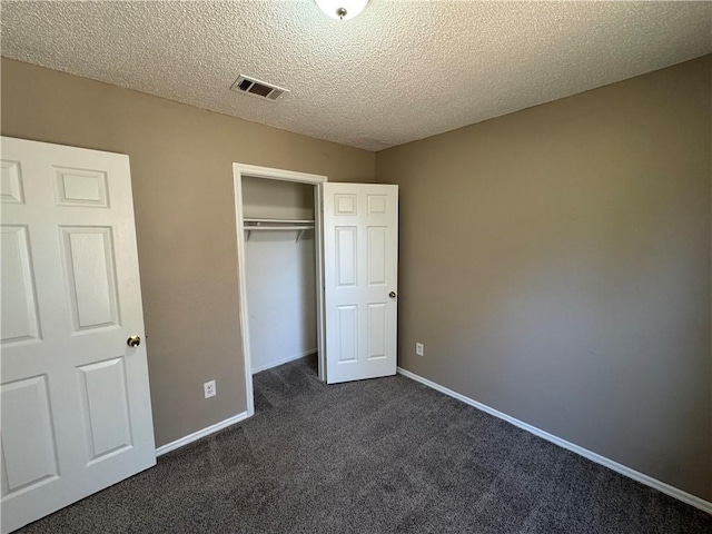 unfurnished bedroom featuring a closet, dark carpet, and a textured ceiling