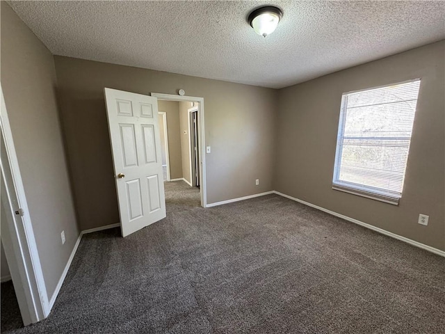 spare room with a textured ceiling and dark carpet