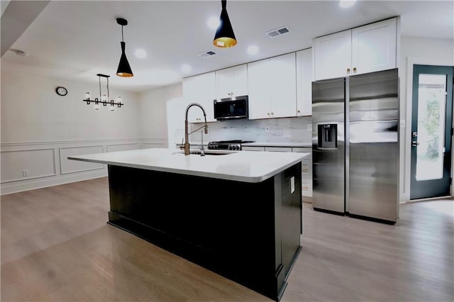 455 Saddle Bow Dr, Lawrenceville, GA 30046 - kitchen featuring stainless steel fridge, a sink, light countertops, a kitchen island with sink, and decorative light fixtures