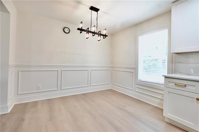 455 Saddle Bow Dr, Lawrenceville, GA 30046 - unfurnished dining area featuring a chandelier, a decorative wall, light wood finished floors, and wainscoting