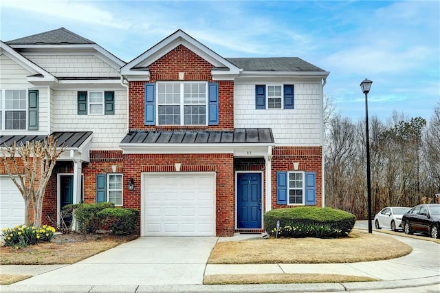 multi unit property featuring a garage, concrete driveway, brick siding, and a standing seam roof