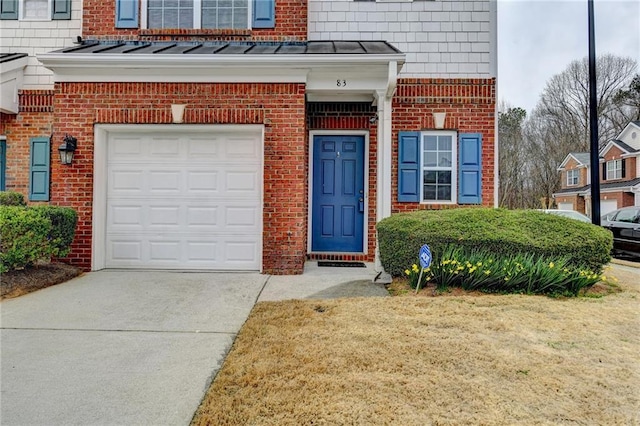 entrance to property with an attached garage, a standing seam roof, concrete driveway, and brick siding