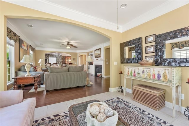 4535 Vanadium Bnd, Cumming, GA 30040 - living area with tile patterned floors, a ceiling fan, arched walkways, crown molding, and a glass covered fireplace
