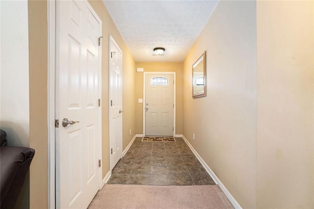 doorway to outside with carpet floors, baseboards, and a textured ceiling