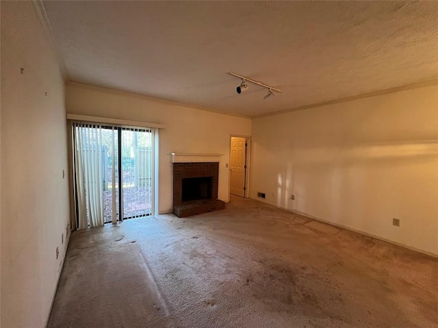 unfurnished living room featuring rail lighting, carpet flooring, a fireplace, and a textured ceiling