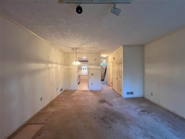 unfurnished room with track lighting, visible vents, and a textured ceiling