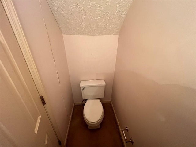 bathroom featuring baseboards, vaulted ceiling, a textured ceiling, and toilet