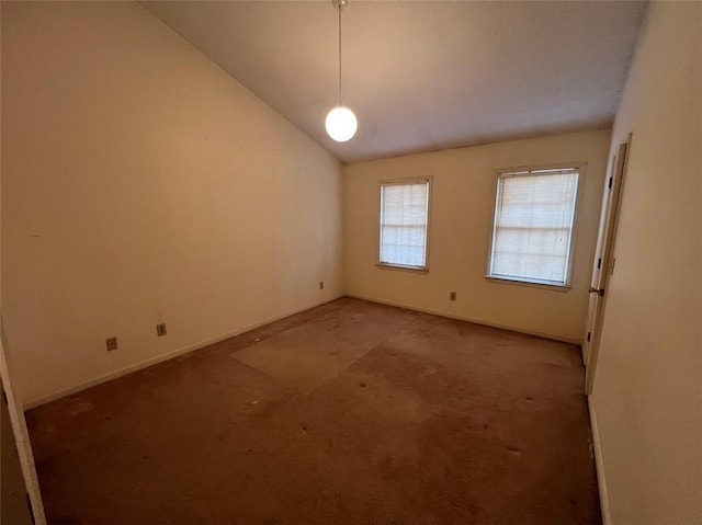 carpeted spare room featuring lofted ceiling and baseboards