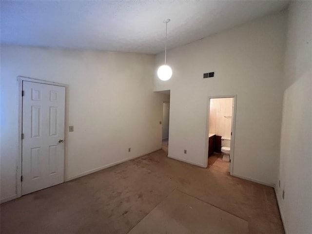 empty room with a high ceiling, visible vents, and baseboards