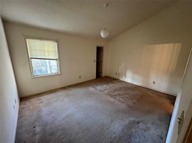 carpeted empty room featuring vaulted ceiling