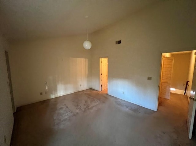 spare room with visible vents, high vaulted ceiling, and concrete flooring