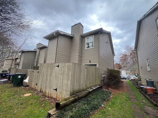 view of property exterior with a chimney and fence