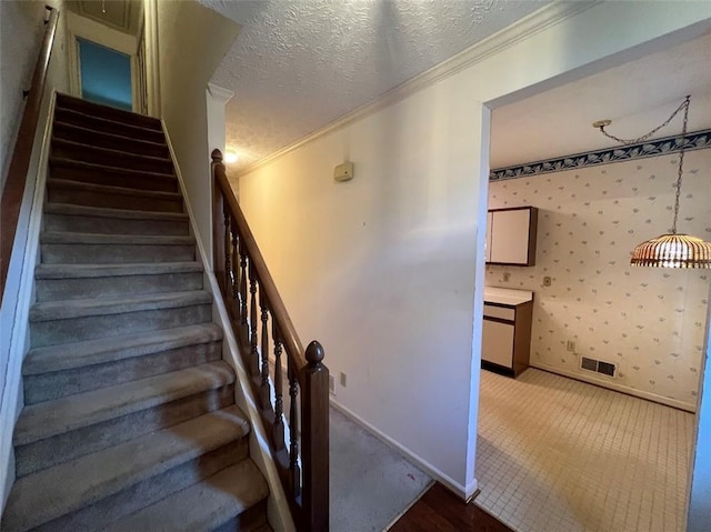 staircase with wallpapered walls, baseboards, a textured ceiling, and ornamental molding