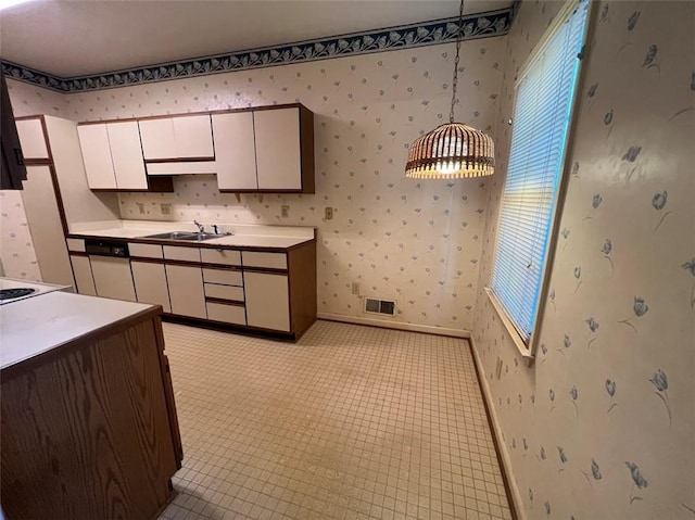 kitchen featuring wallpapered walls, baseboards, visible vents, white cabinets, and a sink