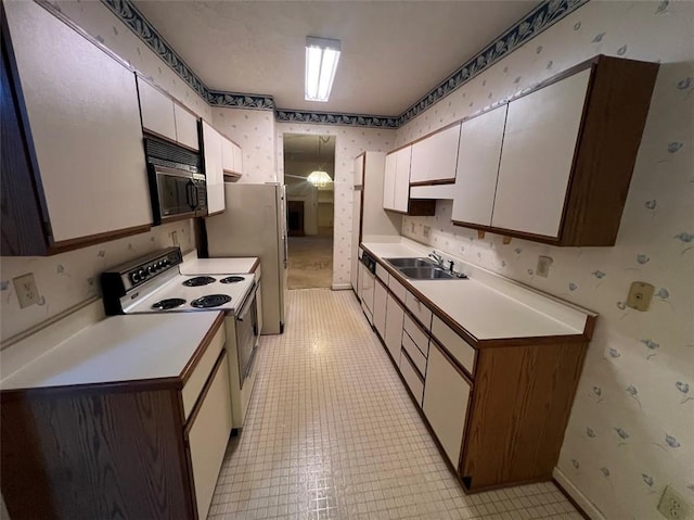 kitchen featuring white appliances, light countertops, a sink, and wallpapered walls