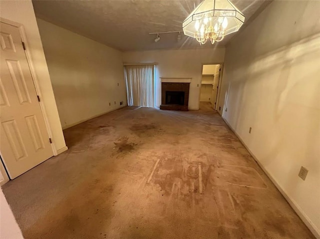 unfurnished living room featuring a fireplace and a notable chandelier