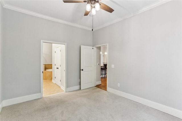 unfurnished bedroom featuring carpet flooring, crown molding, baseboards, ensuite bathroom, and a ceiling fan