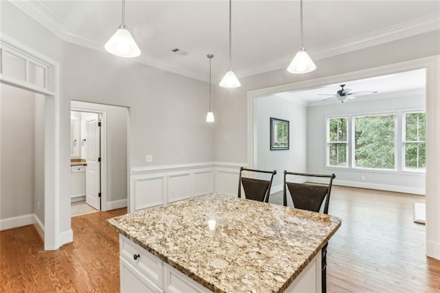 kitchen with light wood-style flooring, crown molding, white cabinets, ceiling fan, and light stone counters
