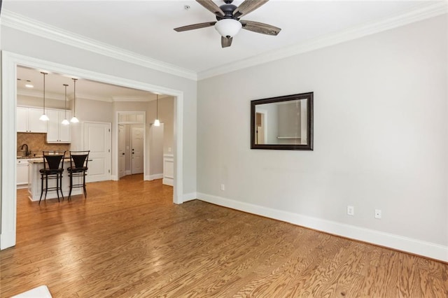 living area with ceiling fan, light wood-style flooring, ornamental molding, and baseboards