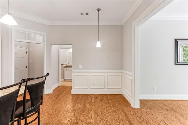 unfurnished dining area with light wood-style floors, ornamental molding, and baseboards