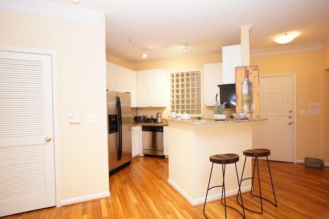 kitchen with white cabinetry, light hardwood / wood-style flooring, rail lighting, light stone counters, and appliances with stainless steel finishes