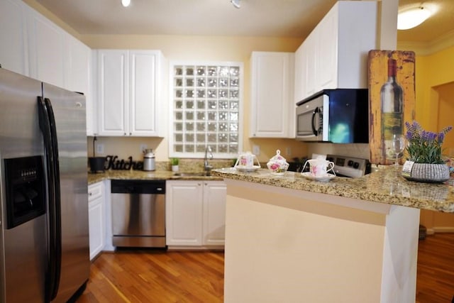 kitchen featuring white cabinetry, light stone countertops, appliances with stainless steel finishes, and light wood-type flooring