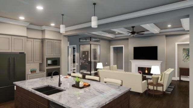 kitchen with light stone counters, a center island with sink, open floor plan, a sink, and a warm lit fireplace