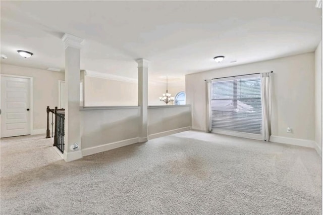 unfurnished room with light colored carpet, a chandelier, and ornate columns