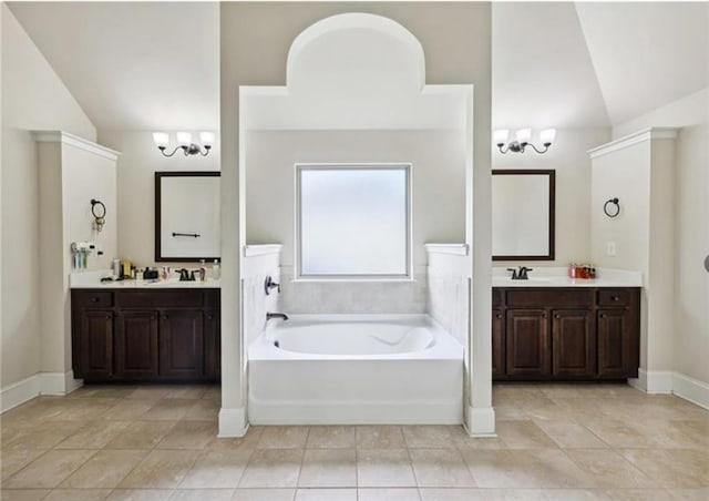 bathroom featuring an inviting chandelier, vanity, a bathing tub, and vaulted ceiling