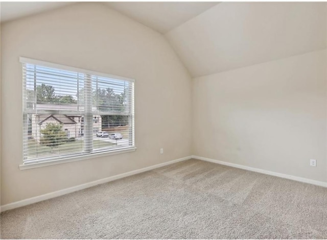 carpeted spare room with vaulted ceiling