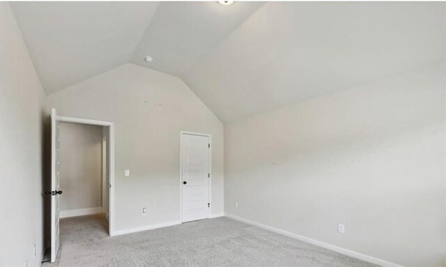 unfurnished bedroom with light colored carpet and lofted ceiling